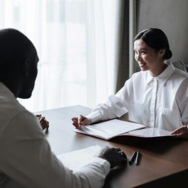 Home A diverse group discussing documents with a professional in a home interior setting.