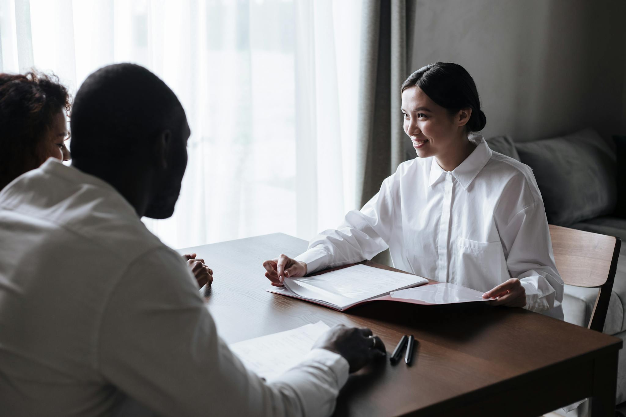 A diverse group discussing documents with a professional in a home interior setting.