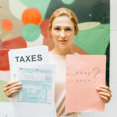 A professional woman holding tax documents and a 'Need Help?' sign, offering tax assistance.