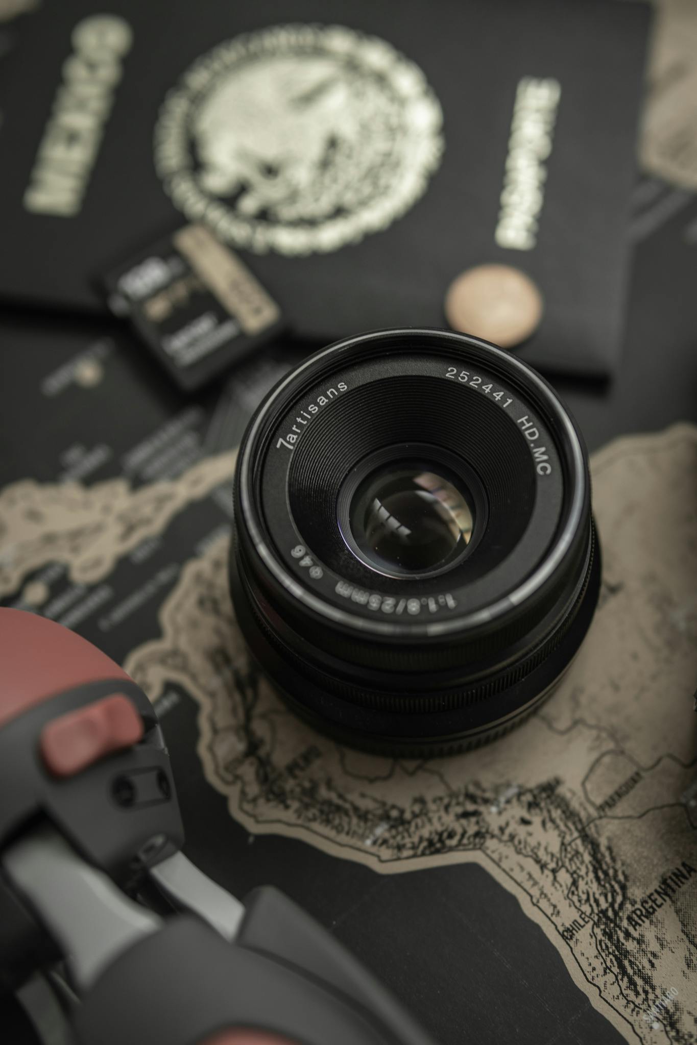 Camera lens and travel essentials on a map, showcasing photography and exploration readiness.